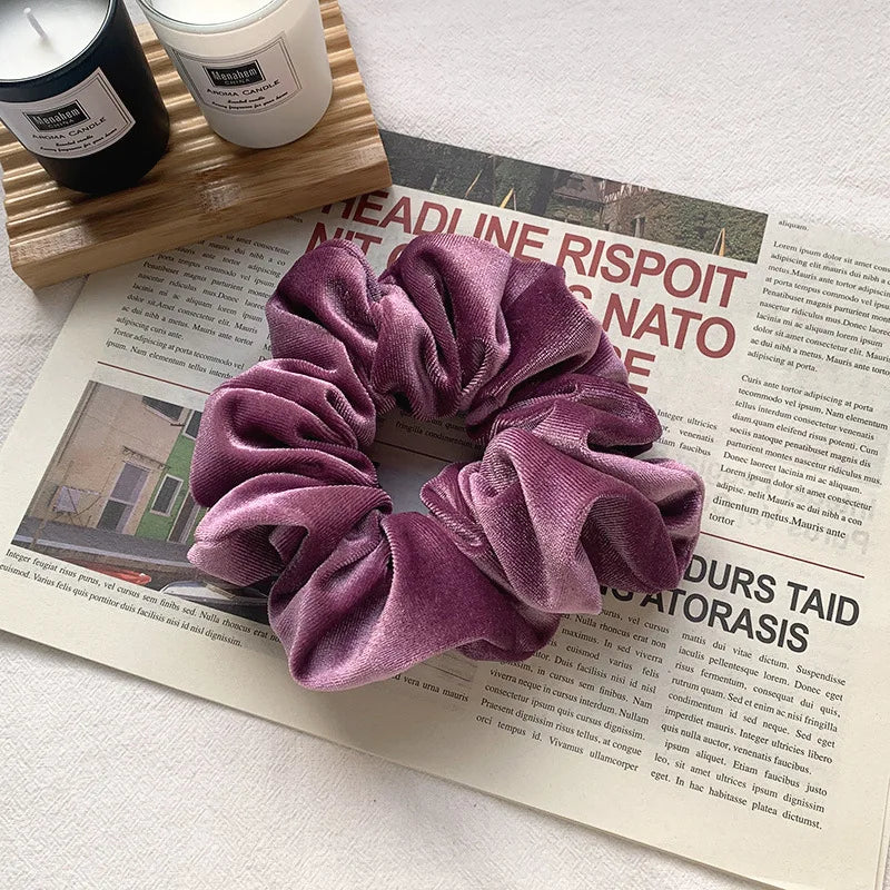 A purple heatless hair curling scrunchie is displayed on a wooden surface next to a printed text.