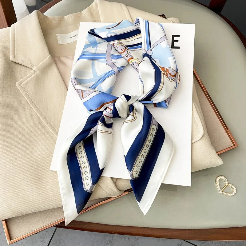 A blue and white striped silk scarf tied in a bow displayed on a white card next to a beige blazer.