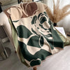 A beige and olive green floral patterned scarf draped over a light-colored piece of furniture.