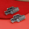 A silver metal clip pin shaped like a vintage black car with chrome details resting on a red fabric background.