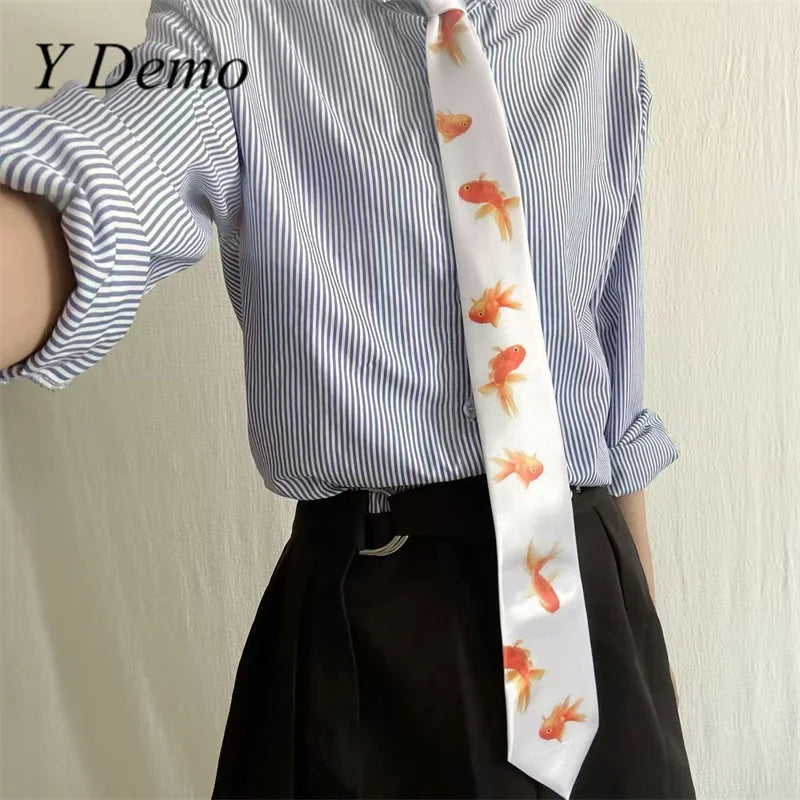 A close-up of a white striped shirt and black skirt with a long neck tie featuring an orange goldfish print.