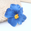 A vibrant blue forget-me-not flower with yellow pollen, resting on a woven natural fiber background.