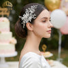 A close-up profile photo of a woman wearing a rhinestone bridal headband with flowers, looking to the right.