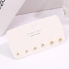 A white card displaying a 3-pack of gold-toned round stud earrings on a white background.