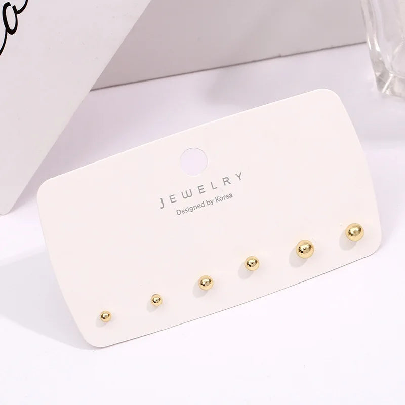 A white card displaying a 3-pack of gold-toned round stud earrings on a white background.