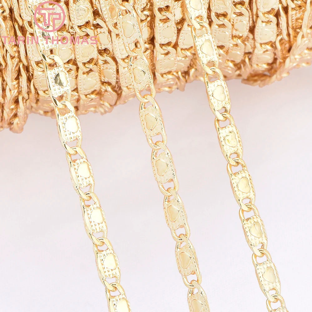 Ein Set aus 18K-Gold-Herzenanhängern und Armreifen, präsentiert auf einer strukturierten goldenen Oberfläche.