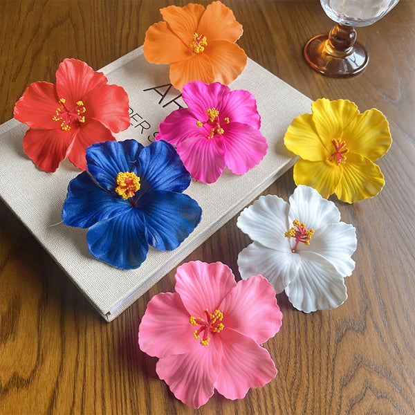 A collection of five vibrant colored flowers displayed on a light-colored surface.