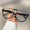 A hand holds a pair of black vintage cat eye sunglasses with UV400 protection against a light background.