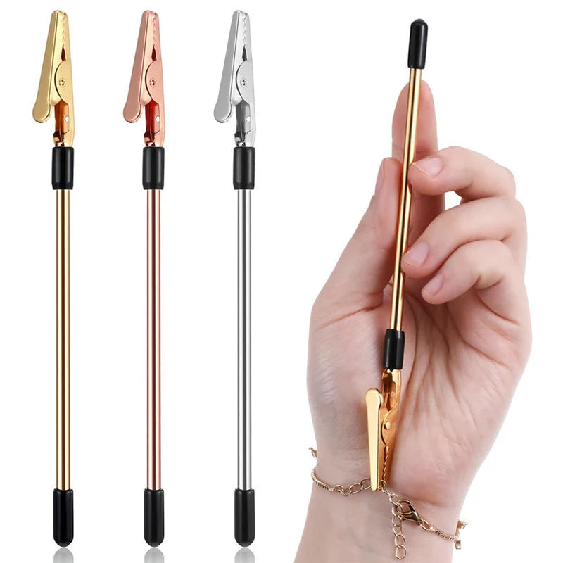 A hand holds a stainless steel jewelry helper tool with a gold-colored finish and black accents.