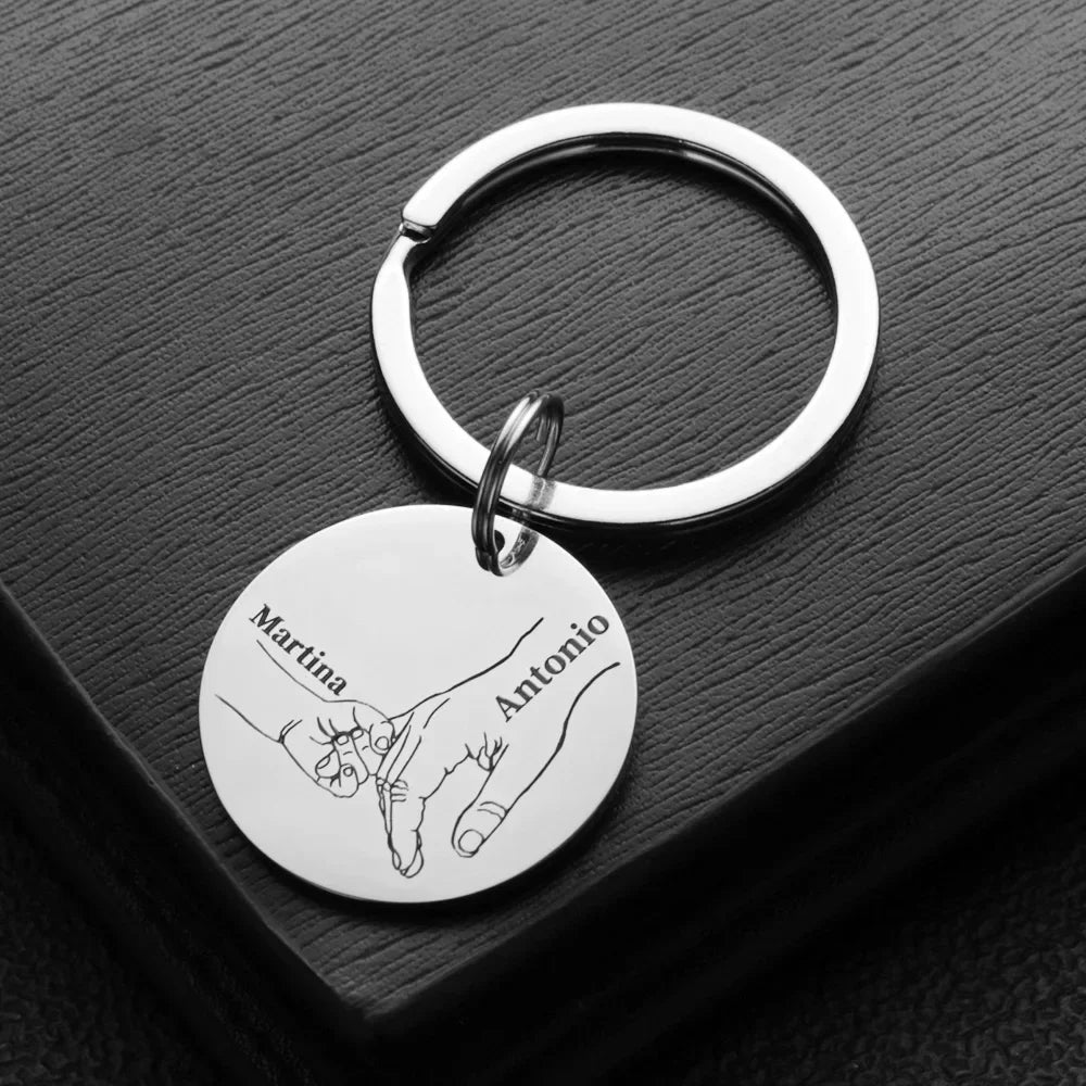 A silver stainless steel keychain featuring a handprint design with the names Martina and Antonio.