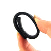A hand is holding a black silicone watch band with a buckle, showing its size and shape.