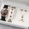 A gold-toned fashion quartz wristwatch with a black leather strap and delicate gold necklaces displayed in a white box.