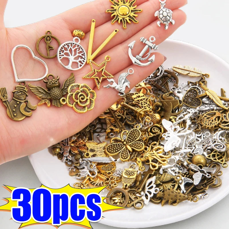 Eine Hand zeigt verschiedene tibetische silberne Anhänger und Perlen für DIY-Schmuck.