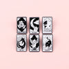 A set of eight black and white tarot-style enamel brooches featuring various animals and symbols like the Wheel of Fortune an