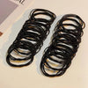 A pair of black durable elastic hair ties coiled and laid out on a light surface.