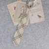 A stack of Japanese plaid neck ties featuring nature and bird designs on light-colored paper.