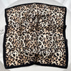A luxury leopard print silk scarf folded and displayed against a white background.