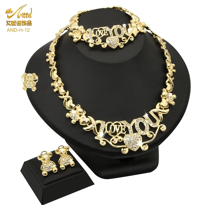 A set of 18K gold heart crystal jewelry including a necklace and earrings displayed on a black surface.