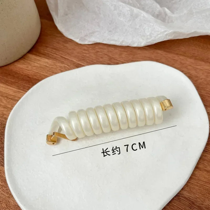 A white rubber braided ponytail holder is displayed on a white ceramic plate with a measurement line indicating 7cm length.