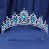 A sparkling crystal rhinestone tiara and headband set featuring blue gemstones against a dark blue background.