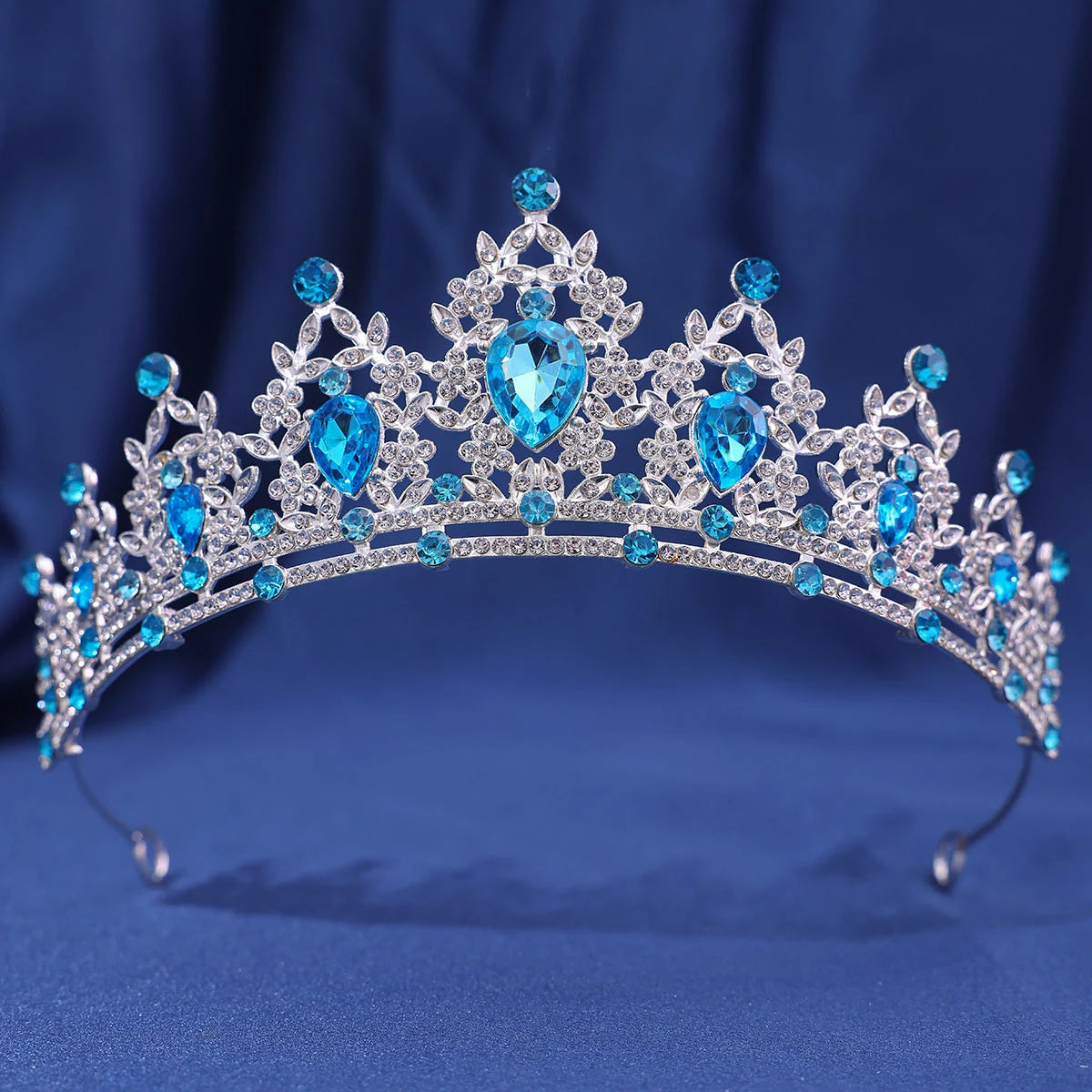 A sparkling crystal rhinestone tiara and headband set featuring blue gemstones against a dark blue background.