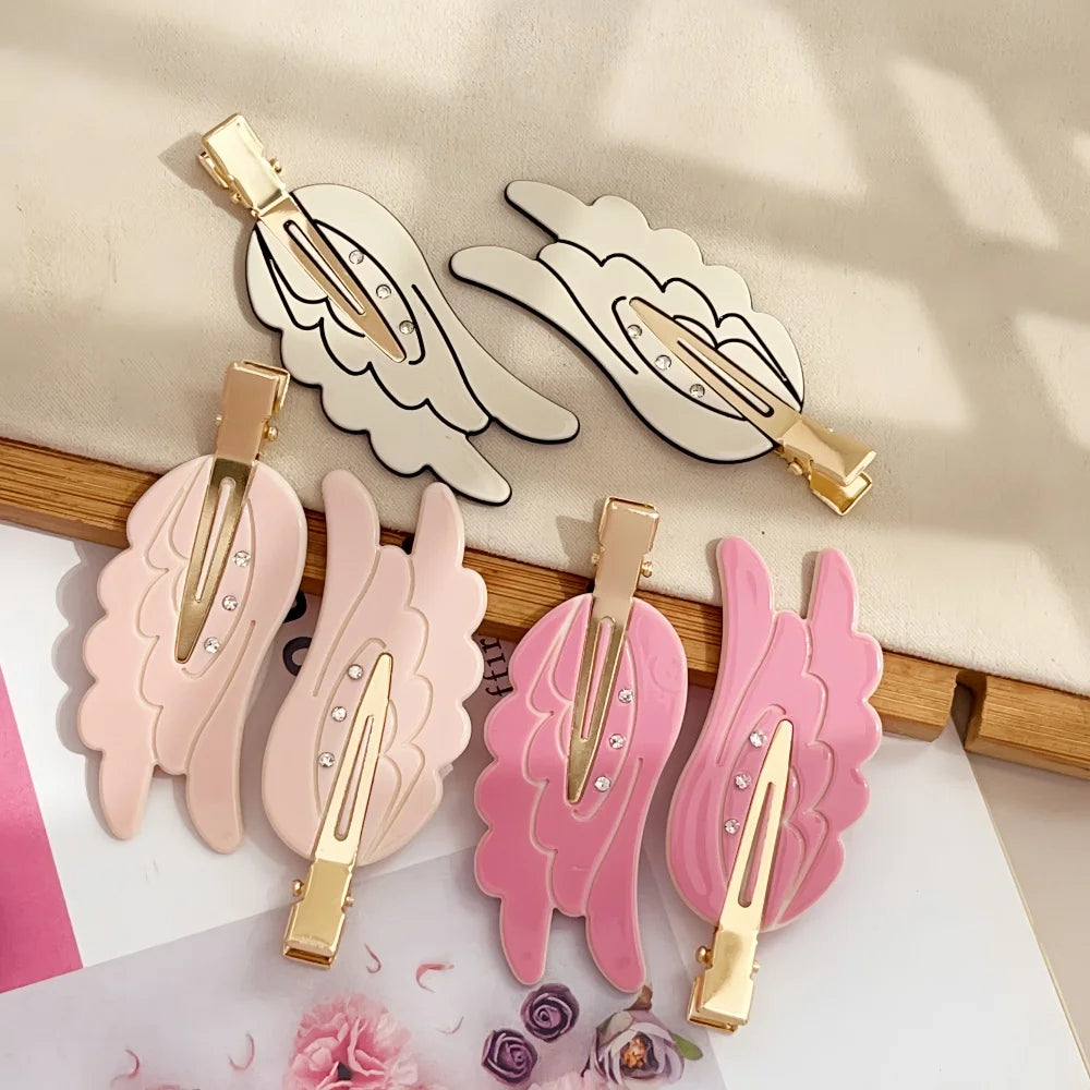 A collection of pink and beige angel wing hair clips and barrettes displayed on a white background.