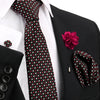 Schwarze und rote gepunktete Krawatte mit weißem Hemd und schwarzem Sakko, mit rosa Blumenanstecknadel.