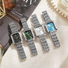 Five silver-toned quartz fashion watches with metal bracelets displayed on a light fabric background.