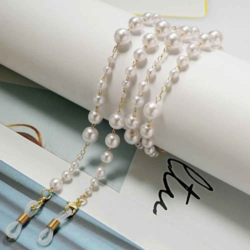 Múltiples cordones elegantes de gafas con perlas y cuentas blancas mostrados sobre un fondo blanco.
