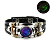 Schwarzes Lederarmband mit silbernen Perlen, goldenen Akzenten und einem zentralen Edelstein, der einen leuchtenden grünen Fi