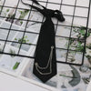 Black classic chain necktie accessory with a silver chain detail displayed on a grid background.