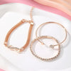 A set of three gold-toned heart charm bracelets with sparkling crystals displayed on a white surface.