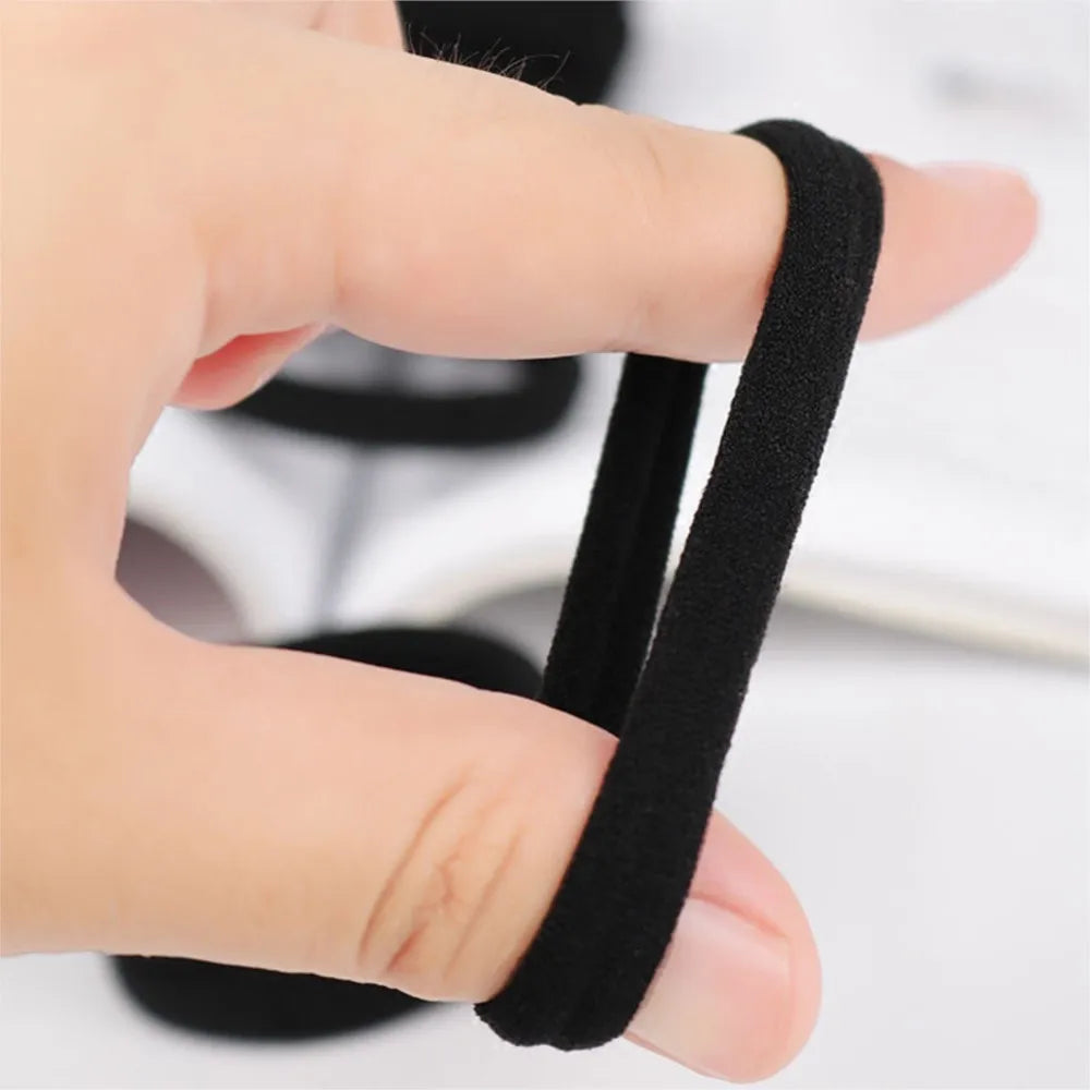 A hand is holding a black seamless hair tie, demonstrating its use for ponytail holders.