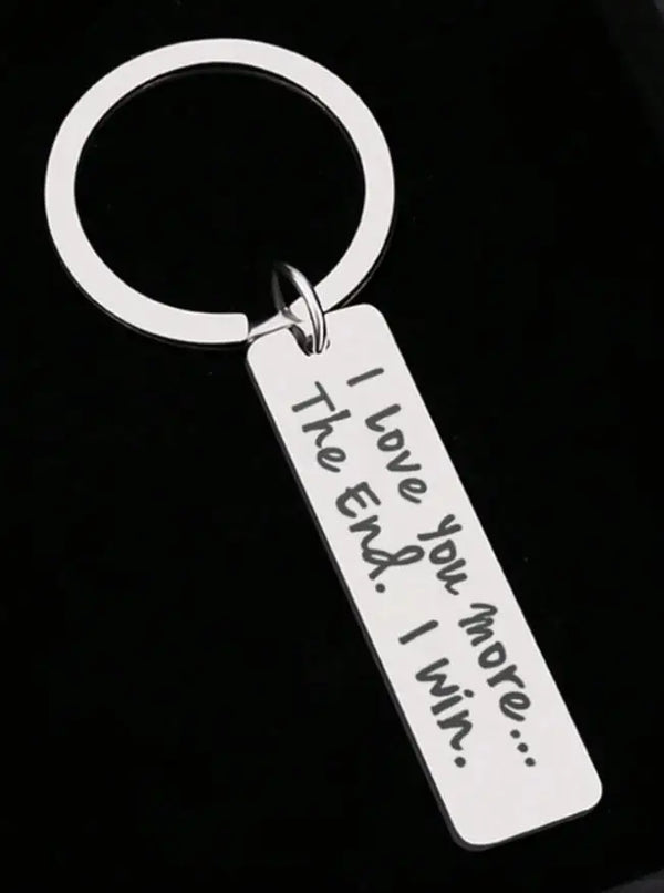 Silver keychain with a loop and a tag engraved with the message I love you more I win