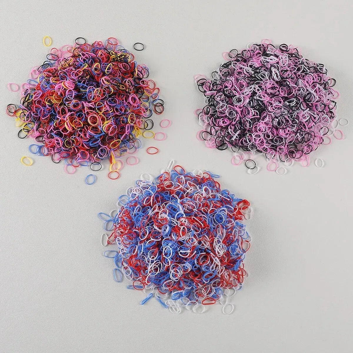 A pile of colorful disposable rubber hair ties in various shades of pink, purple, red, and blue.