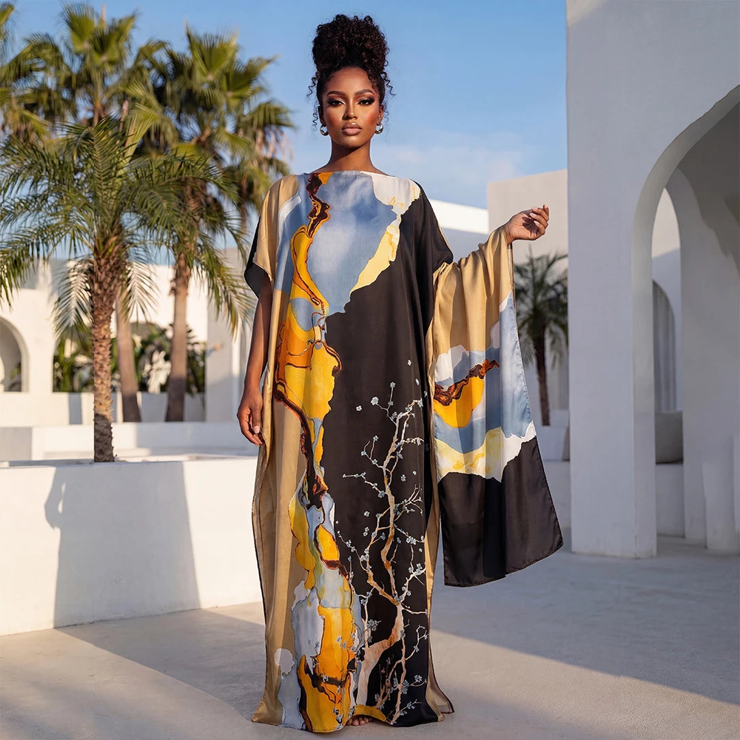 Une femme modélise une longue robe noire à motifs floraux abstraits jaune et bleu, à l'extérieur contre une architecture blan