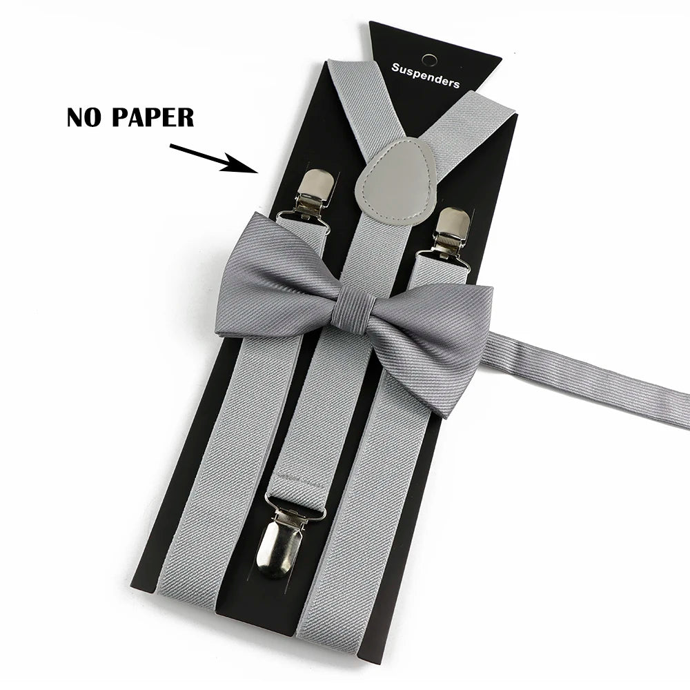 A set of gray polyester suspenders with bow ties displayed on a black card.
