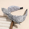 A black and white leopard print retro bow hairband is shown against a light background.
