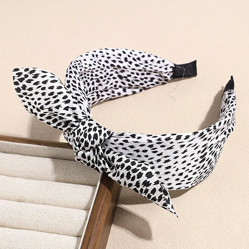 A black and white leopard print retro bow hairband is shown against a light background.