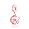 Un delicado dije de oro rosa con un diseño floral rosa y una perla oval.