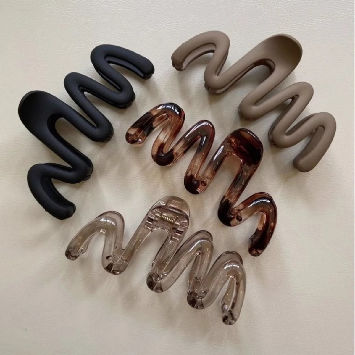 A collection of three high-gloss amber hair clips in different shades and finishes arranged in a wavy pattern.