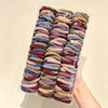 A plastic bag filled with numerous solid color elastic hair ties for ponytails.