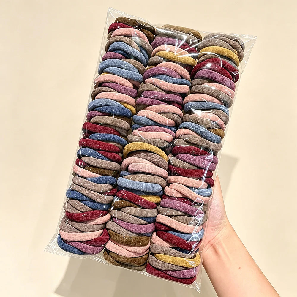 A plastic bag filled with numerous solid color elastic hair ties for ponytails.