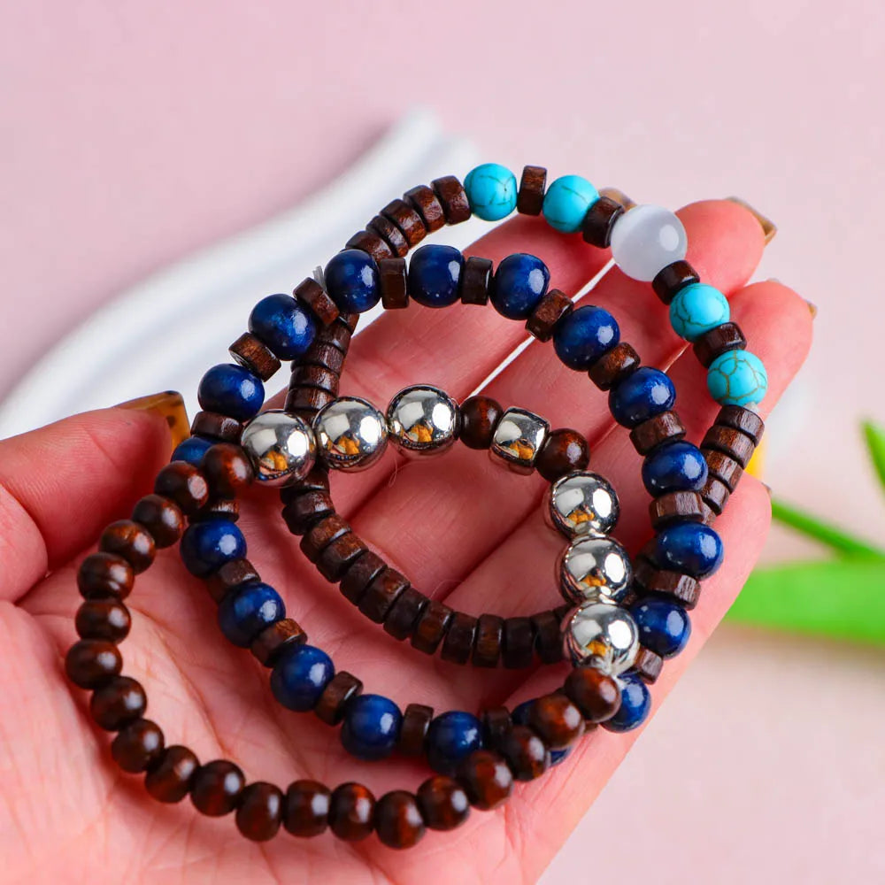A hand holds several fashion elastic wood bead bracelets featuring blue, brown, and turquoise beads.