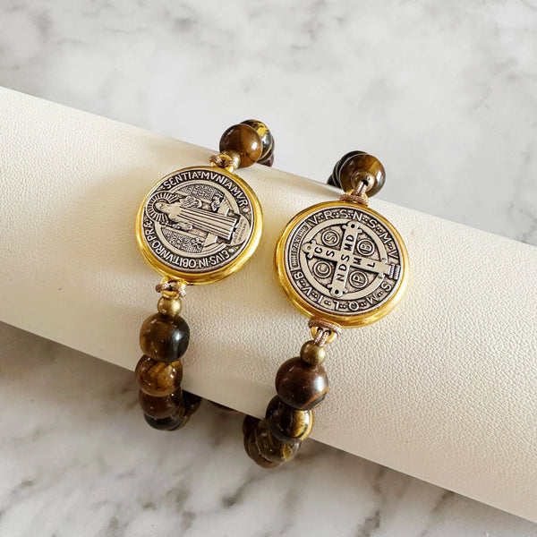 Un ensemble de bracelets-médaillons dorés avec des designs complexes et des perles brun foncé.