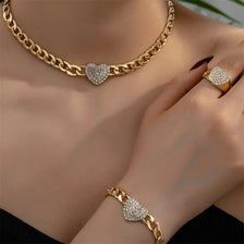 Primer plano de una cadena de oro con dije de corazón y una pulsera a juego en la mano de una mujer.