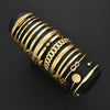 A stack of gold geometric minimalist bracelets on a black background.