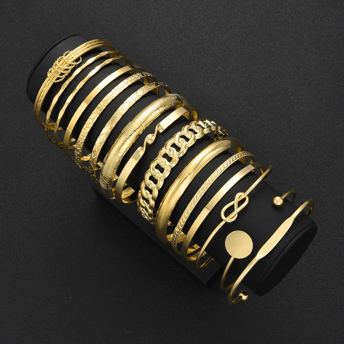A stack of gold geometric minimalist bracelets on a black background.