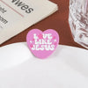 Broche en émail cœur rose avec le texte 'LOVE LIKE JESUS' entouré de petites fleurs roses