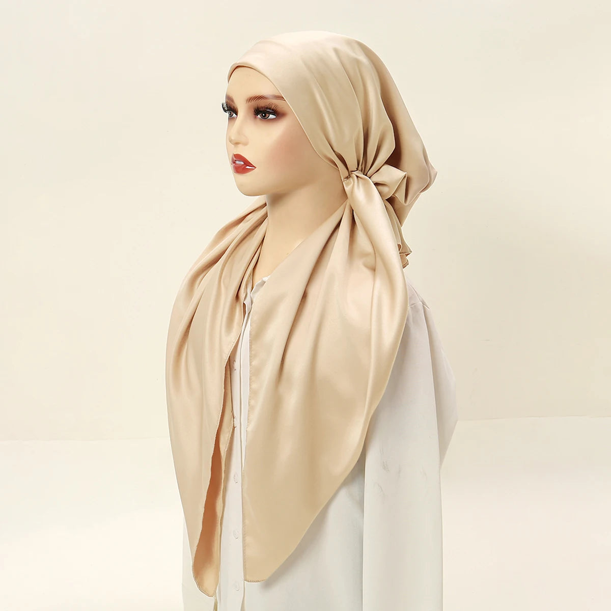 A model wearing a beige satin silk hijab with a white top.
